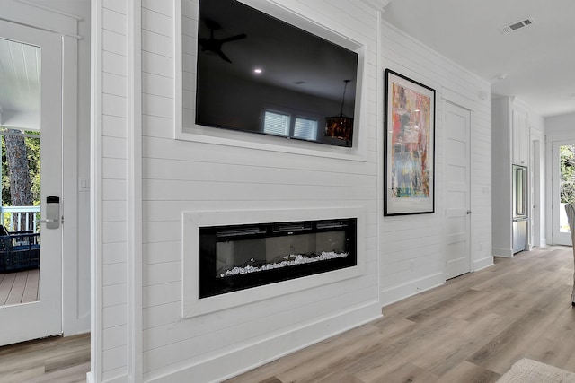 unfurnished living room featuring baseboards, visible vents, wood finished floors, and a glass covered fireplace