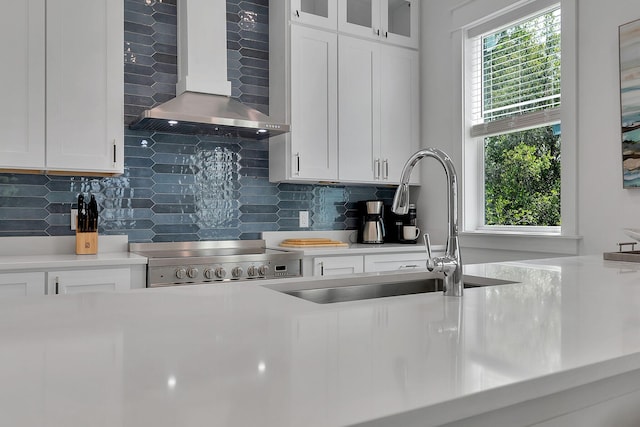 kitchen featuring a wealth of natural light, light countertops, wall chimney exhaust hood, and stove