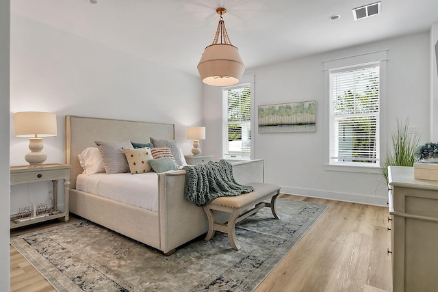 bedroom featuring multiple windows, wood finished floors, visible vents, and baseboards