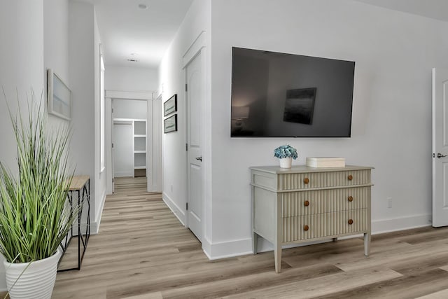 hallway featuring light wood finished floors and baseboards