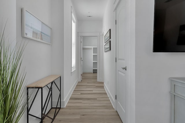 corridor featuring light wood-type flooring and baseboards