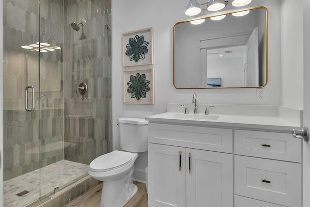 bathroom with toilet, a stall shower, wood finished floors, and vanity