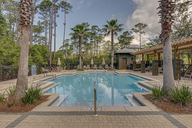 community pool featuring a patio area, fence, an outdoor structure, and a pergola