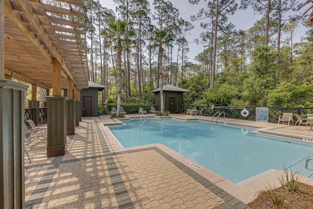 pool with a patio area, an outdoor structure, and a pergola