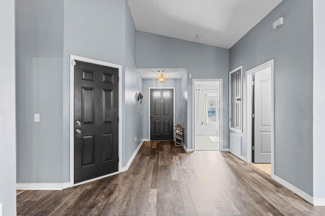 foyer with lofted ceiling, wood finished floors, and baseboards