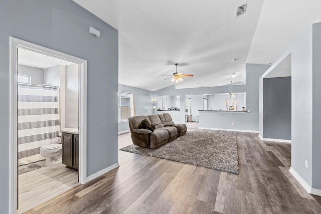 living room with vaulted ceiling, ceiling fan, wood finished floors, and visible vents