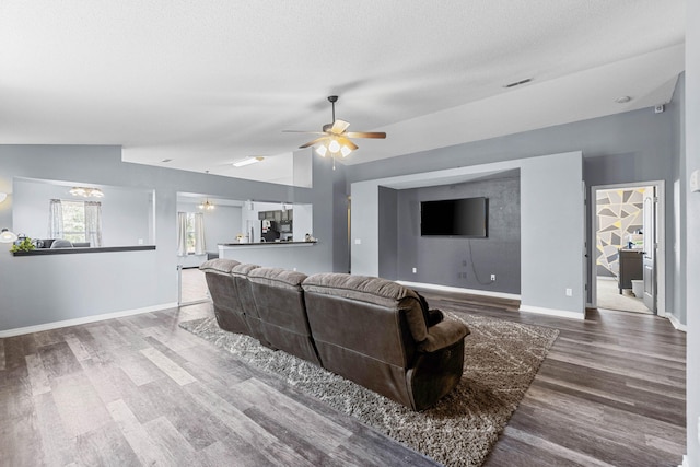 living area featuring lofted ceiling, wood finished floors, a ceiling fan, and baseboards