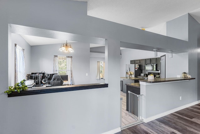 kitchen featuring lofted ceiling, stainless steel fridge, black microwave, and wood finished floors