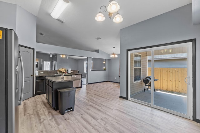 kitchen with light wood-style floors, dark countertops, freestanding refrigerator, and a notable chandelier