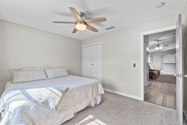 carpeted bedroom with a textured ceiling, a ceiling fan, visible vents, baseboards, and a closet