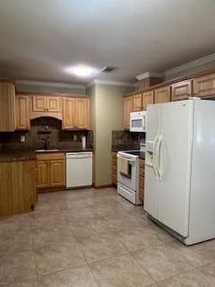 kitchen with dark countertops, white appliances, ornamental molding, and a sink