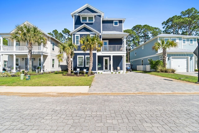 coastal inspired home with board and batten siding, decorative driveway, a front lawn, and a garage