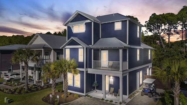 view of front of house featuring a patio, metal roof, a balcony, a garage, and driveway