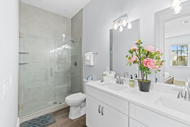 full bath featuring a sink, a shower stall, toilet, and wood finished floors