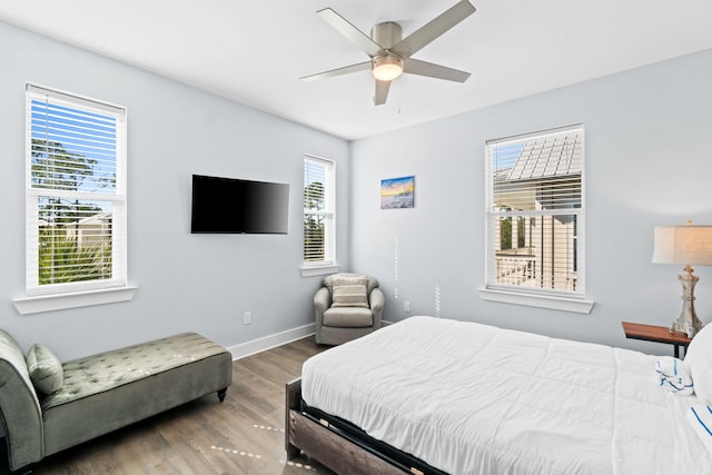 bedroom with a ceiling fan, multiple windows, baseboards, and wood finished floors