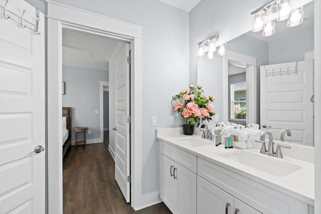 bathroom featuring double vanity, connected bathroom, a sink, and wood finished floors