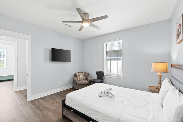 bedroom featuring a ceiling fan, visible vents, baseboards, and wood finished floors