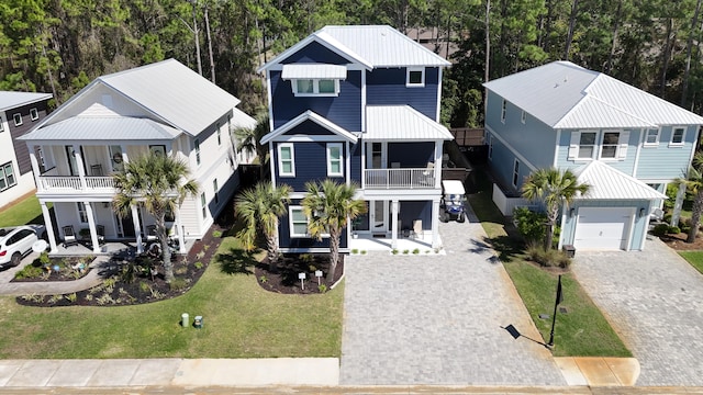 raised beach house featuring metal roof, driveway, a balcony, and a front lawn