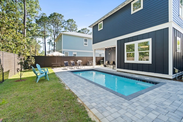 view of swimming pool featuring a fenced in pool, a fenced backyard, a patio, and a lawn