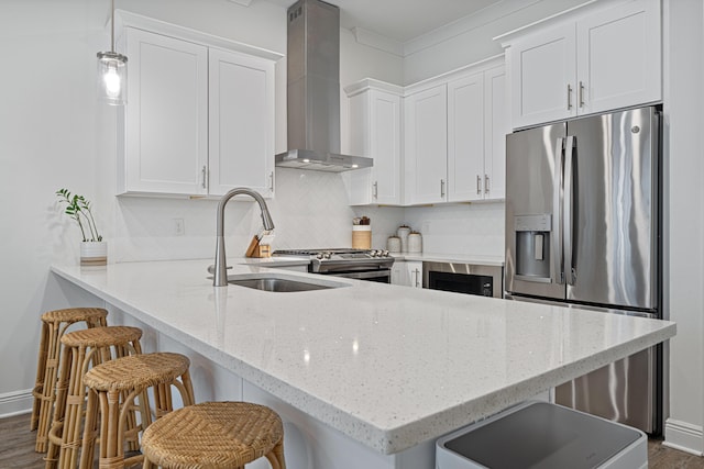 kitchen with stainless steel appliances, backsplash, white cabinetry, a sink, and wall chimney exhaust hood