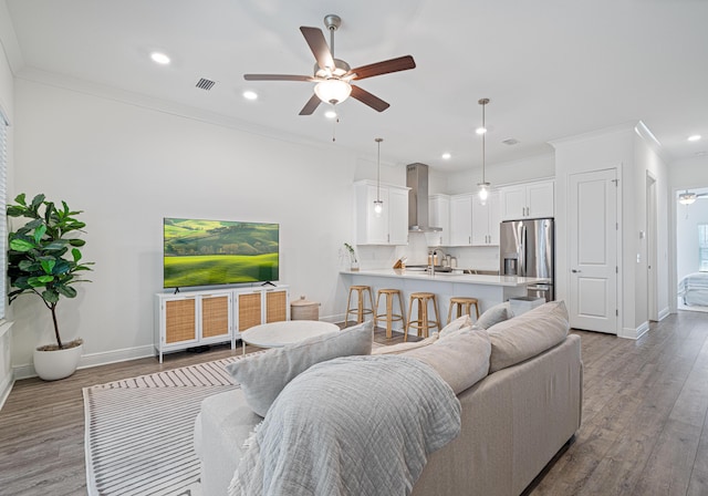 living room with ornamental molding, ceiling fan, baseboards, and wood finished floors