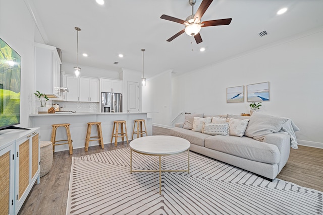 living room with ornamental molding, recessed lighting, ceiling fan, and light wood-style flooring