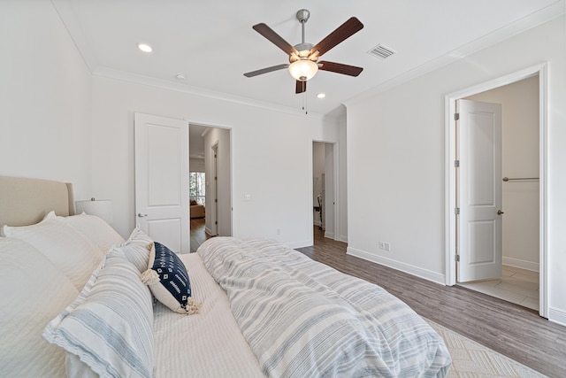 bedroom featuring ornamental molding, visible vents, baseboards, and wood finished floors