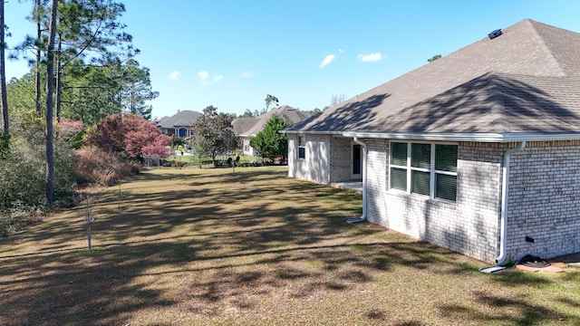 279 Tournament Ln, Freeport, FL 32439 - view of home's exterior featuring brick siding, a shingled roof, fence, and a yard