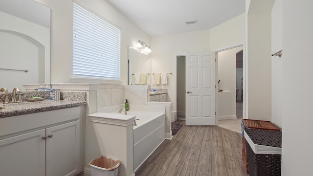 279 Tournament Ln, Freeport, FL 32439 - bathroom featuring visible vents, a garden tub, vanity, and wood finished floors