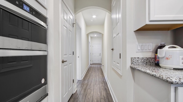 279 Tournament Ln, Freeport, FL 32439 - hallway with baseboards, arched walkways, and wood finished floors