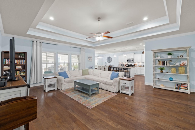 living room with dark wood-style floors, ceiling fan, ornamental molding, and a raised ceiling