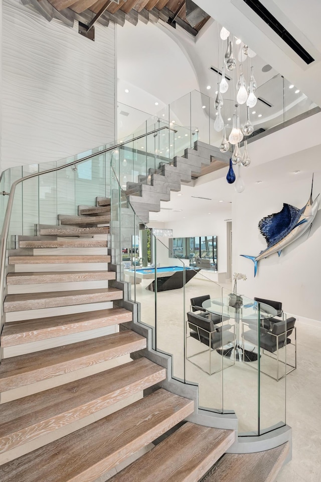 staircase featuring a towering ceiling, a notable chandelier, and recessed lighting