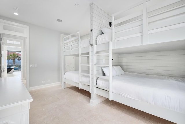 bedroom featuring concrete flooring, recessed lighting, and baseboards