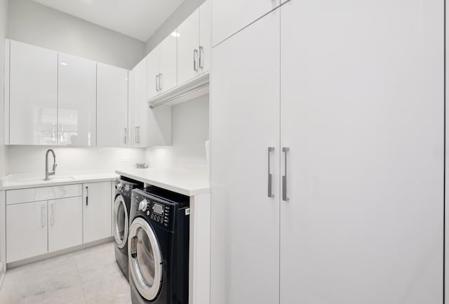 laundry room featuring cabinet space, light tile patterned floors, a sink, and independent washer and dryer