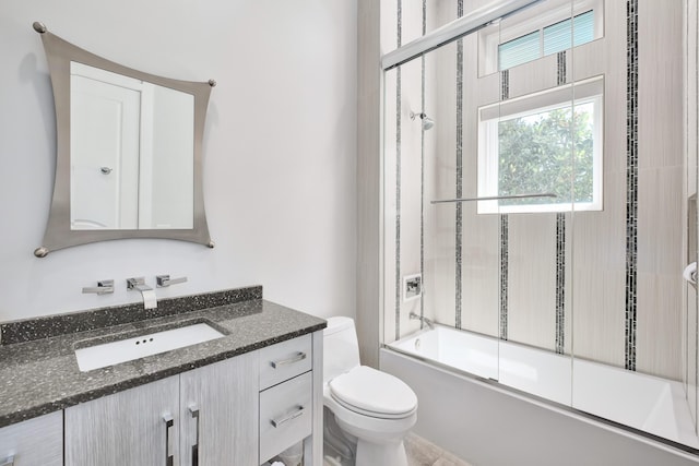 bathroom with shower / bath combination with glass door, vanity, and toilet