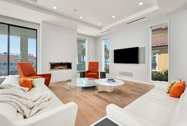 living area featuring recessed lighting, a fireplace, baseboards, and wood finished floors