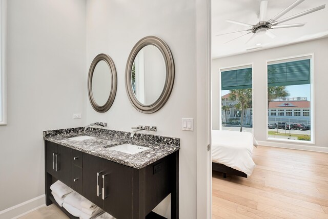 full bathroom featuring double vanity, a sink, baseboards, and wood finished floors