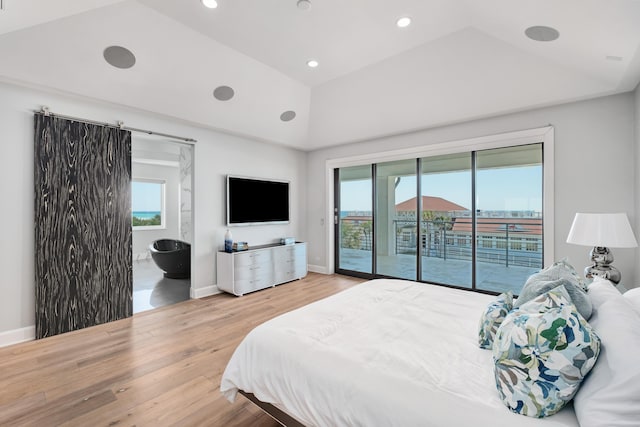 bedroom with access to exterior, lofted ceiling, a barn door, wood finished floors, and baseboards