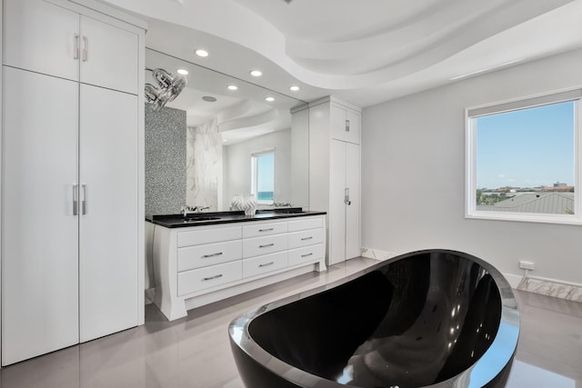 bathroom featuring double vanity, recessed lighting, decorative backsplash, a sink, and a freestanding tub