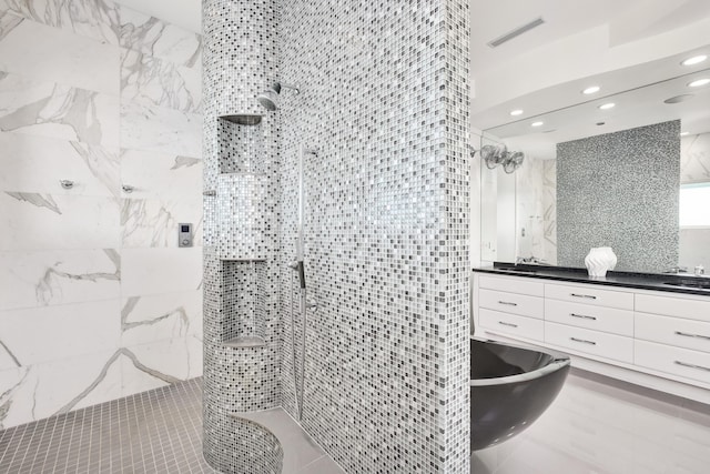 bathroom featuring visible vents, a tile shower, and vanity