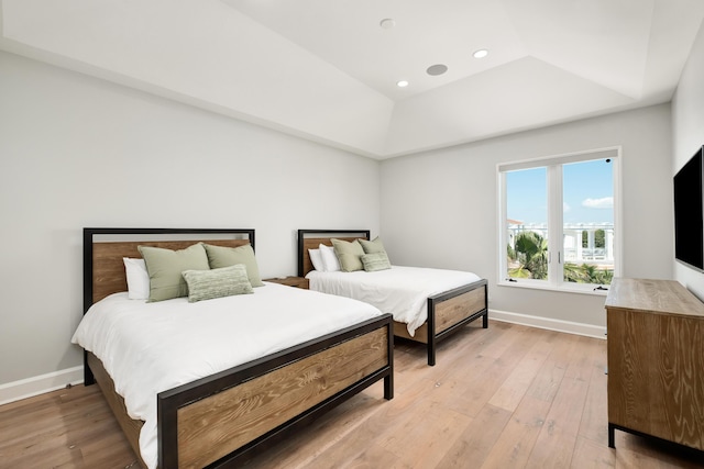 bedroom with baseboards, recessed lighting, a raised ceiling, and light wood-style floors