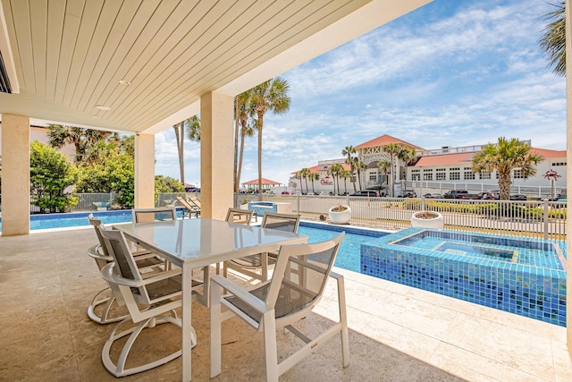 view of swimming pool featuring outdoor dining space, a pool with connected hot tub, a patio area, and fence