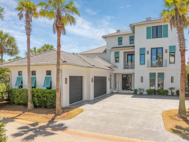 view of front of property featuring decorative driveway, an attached garage, and stucco siding