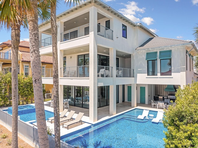 rear view of property with a pool with connected hot tub, a patio, fence, and stucco siding