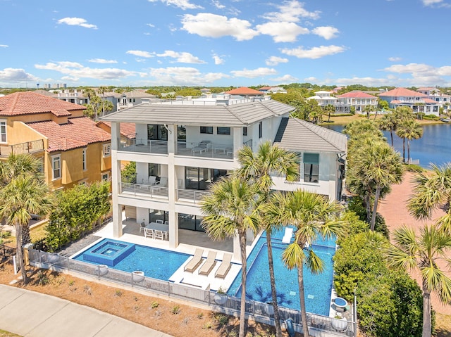 rear view of property featuring a fenced backyard, a balcony, an outdoor hot tub, a residential view, and a patio area