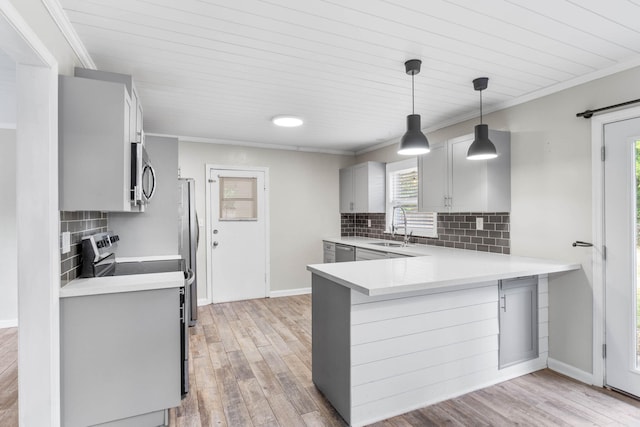 kitchen with appliances with stainless steel finishes, gray cabinets, a sink, and light wood finished floors