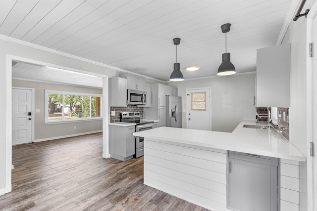 kitchen with dark wood finished floors, appliances with stainless steel finishes, ornamental molding, light countertops, and backsplash