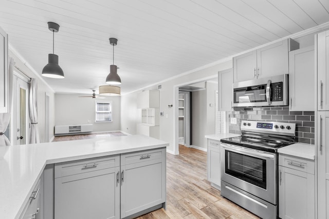 kitchen featuring light wood finished floors, appliances with stainless steel finishes, ornamental molding, light countertops, and backsplash