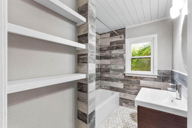 full bath featuring tile walls, ornamental molding, vanity, a tub, and tile patterned flooring