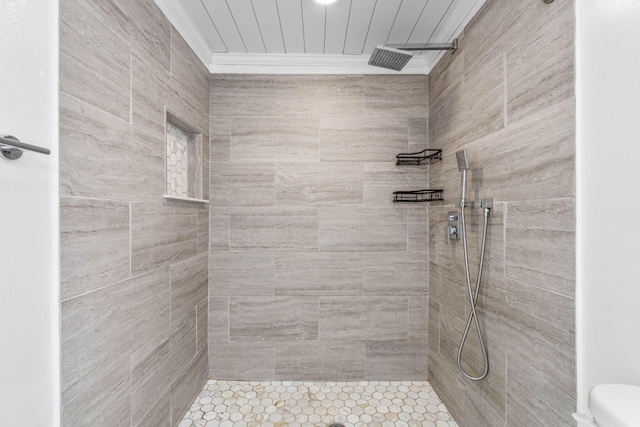 bathroom with toilet, a tile shower, and crown molding